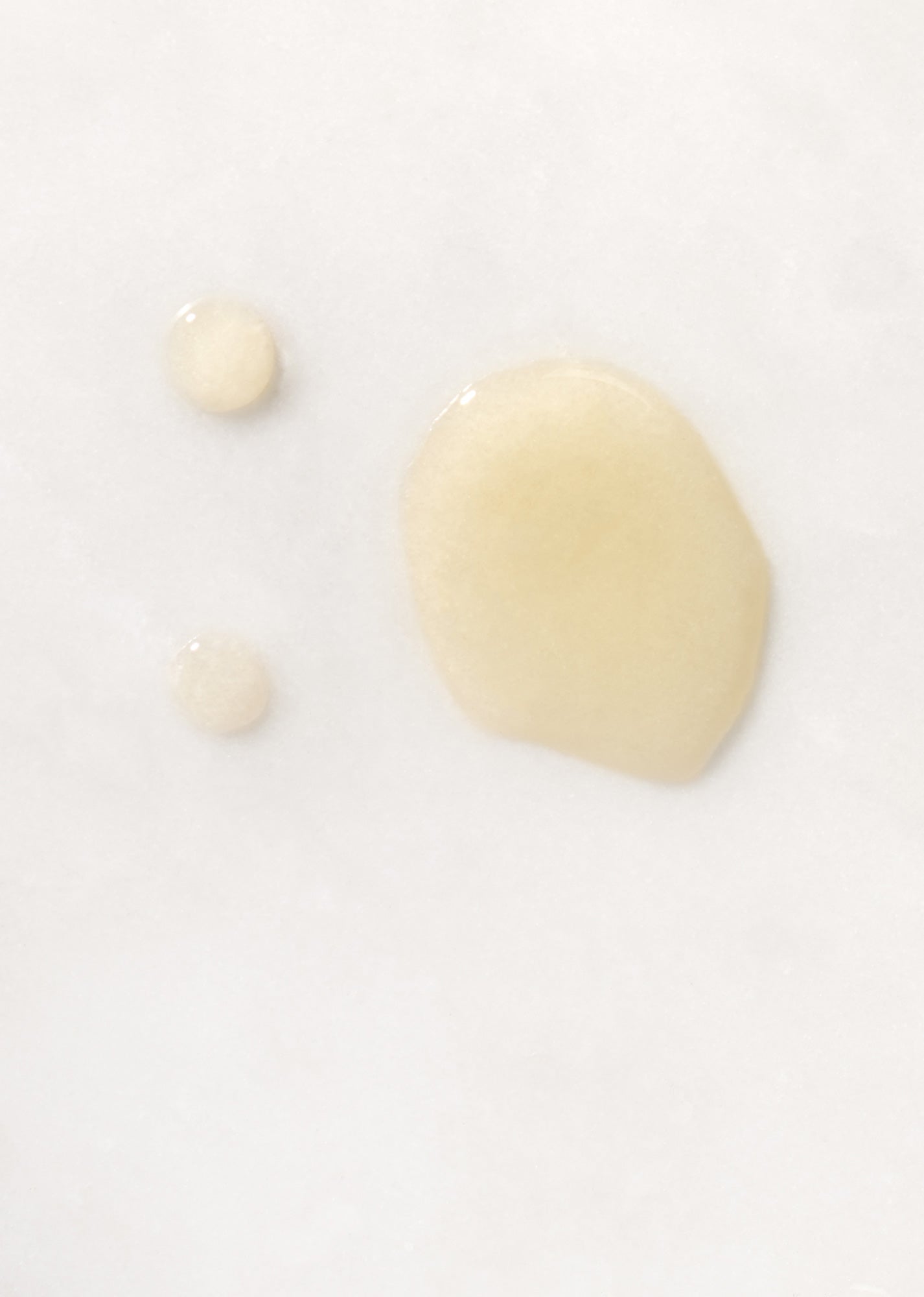 Drops of golden Olio Per Il Corpo Body Oil on white background.
