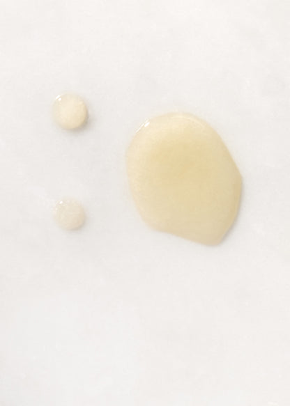 Drops of golden Olio Per Il Corpo Body Oil on white background.